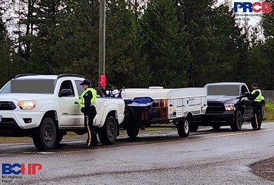 Two BC Highway Patrol officers have two pickup trucks stopped at a checkstop