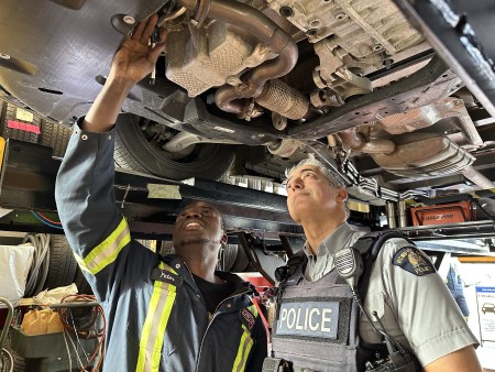 Photo of RCMP officer and mechanic inspecting catalytic converter